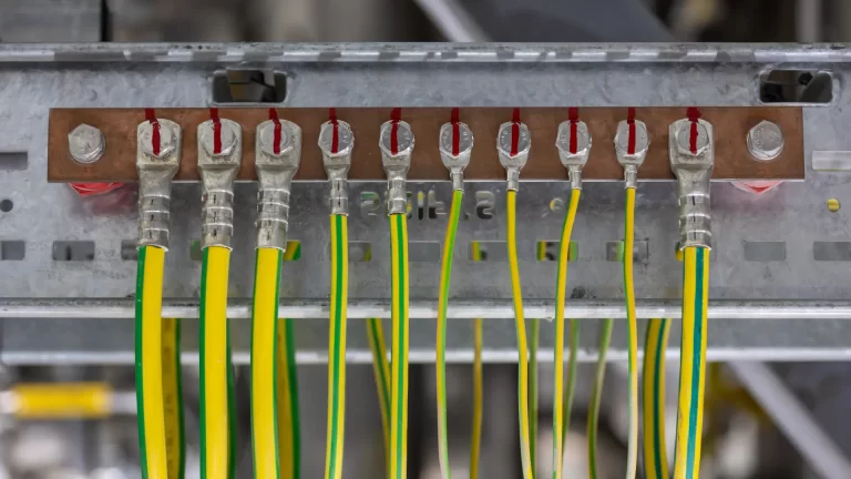 Imagem de barramento de aterramento elétrico com vários cabos verde-amarelo fixados por terminais, utilizado na proteção elétrica de instalações
